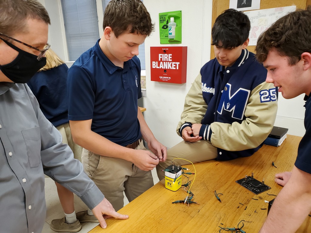 Mr. Dennis checks in with a group during an electricity lab in Physics I