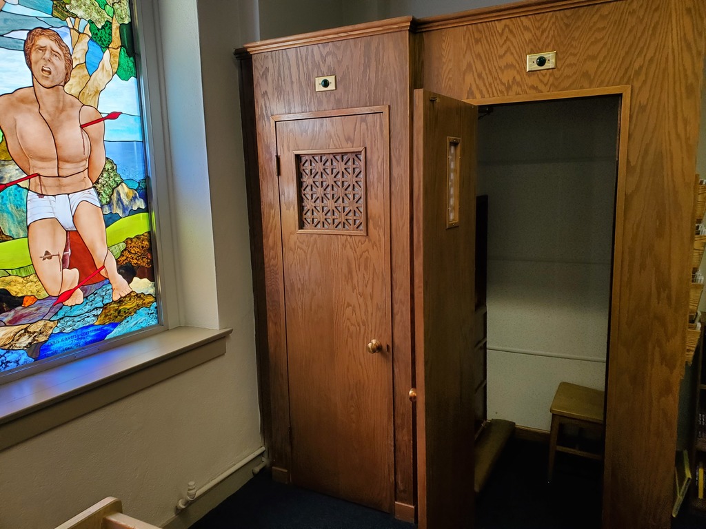 Open door to confessional w/stained glass window in background
